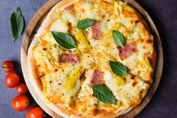 Tasty pizza homemade italian food style, pizza cheese ham and pineapple fruit cooking ingredients tomatoes basil on black background. Top view Flat lay