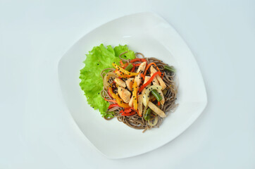 Plate of noodles with meat and vegetables isolated on white background, top view