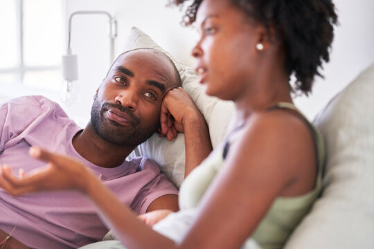 Black man and woman talking in bed