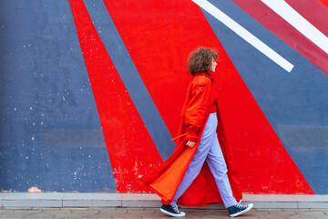 Stylish female walking against wall with abstract ornament