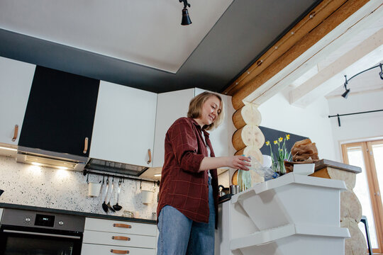 Housewife throwing bottle into trash bin for recycling