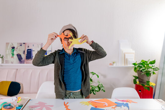Boy creating art with colorful paper spending time at home