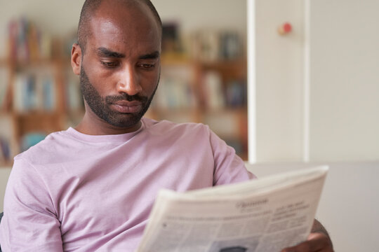 Afro American male reading morning newspaper.