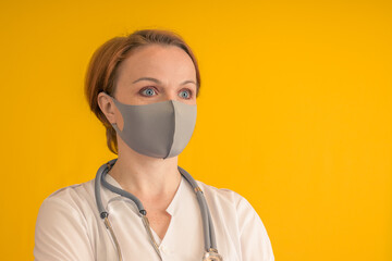 The doctor in a gray mask with a stethoscope. On a yellow background.