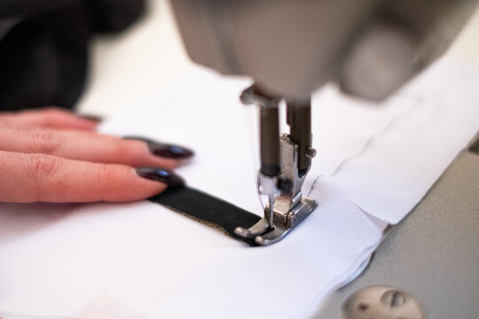 Close up of a tailor woman using sewing machine in her sewing atelier
