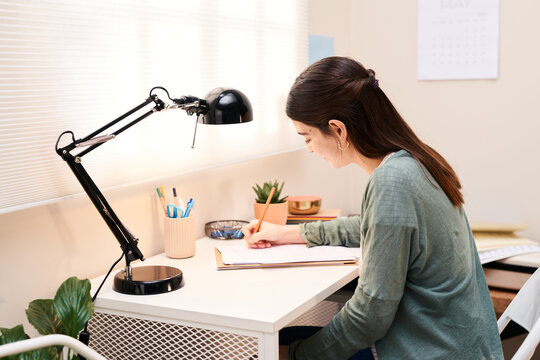 Girl taking notes in document.