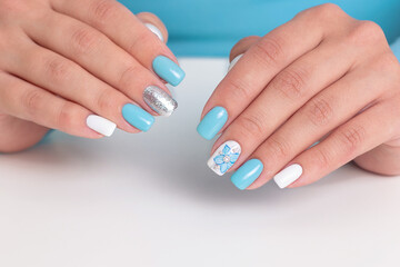 Beautiful female hands with romantic manicure nails, blue and white gel polish
