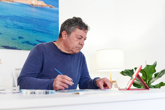 Mature man watching a painting tutorial online