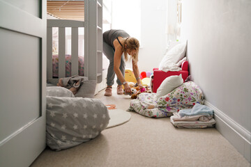 Cleaning lady tidying children's bedroom