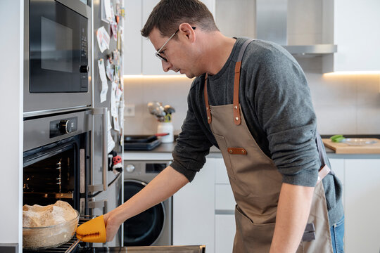 Man introducing a loaf of bread dough in the oven.