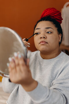 Charming woman doing makeup in front of mirror