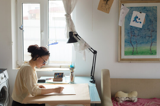 woman artist draws by the window
