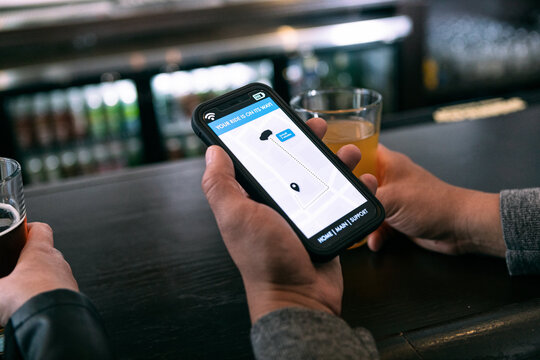 Brewery: Couple Using Cell Phone To Order Rideshare From Bar
