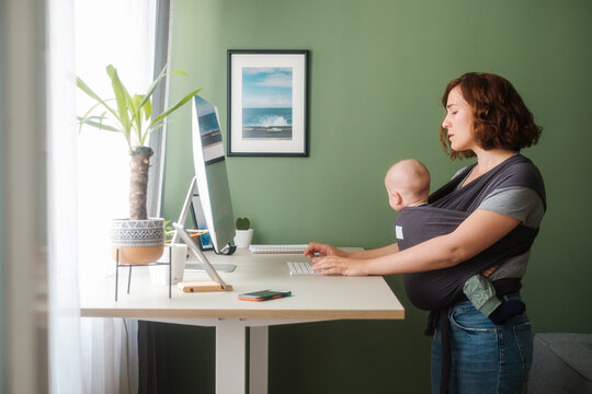 Woman With A Baby Standing At The Desk