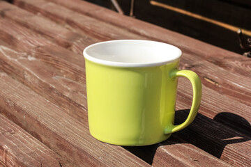 A light green mug stands on a bench during a break in the campaign.