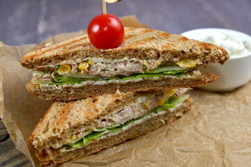 Club Sandwich with Cheese, PIckled Cucumber, Tomato and Smoked Meat. Garnished with sauce on wooden table
