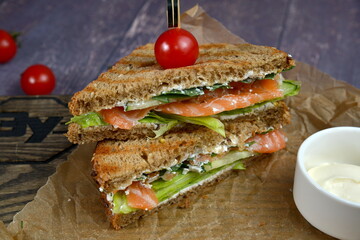 Club Sandwich with Cheese, PIckled Cucumber, Tomato and Smoked Meat. Garnished with sauce on wooden table