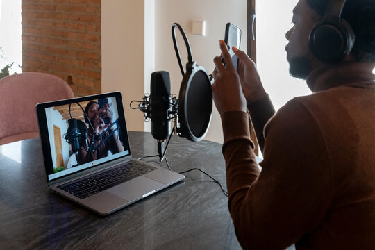 Black singer using smartphone near laptop