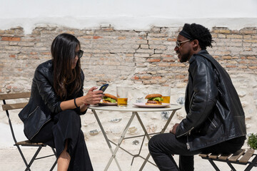 Multiracial couple eating burgers during date