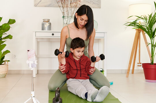 Mom vlogging her son using dumbbells at home