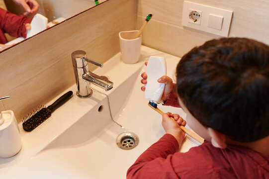 Boy putting toothpaste on his toothbrush