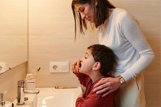 Mom watching her son brush his teeth