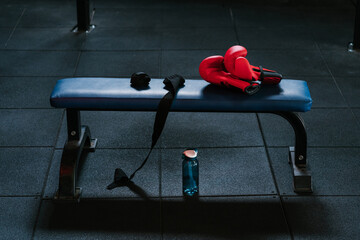 Boxing gloves and bandages on bench in modern gym