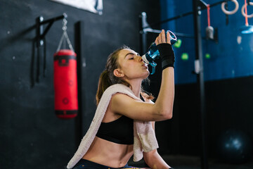 Sporty woman drinking water in boxing club