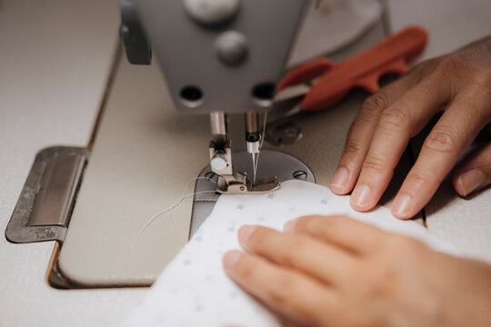 Selective focus on hands embroidering fabric and a pair of tailor's scissors at the same time.