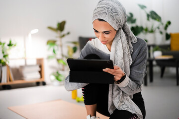 Muslim sportswoman using tablet during break