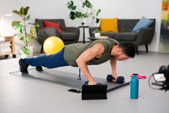 Man exercising with dumbbells during online training at home