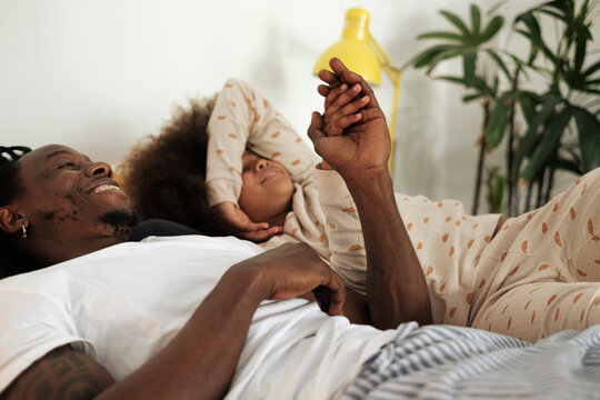 Close up of a father and his daughter with joined hands in bed