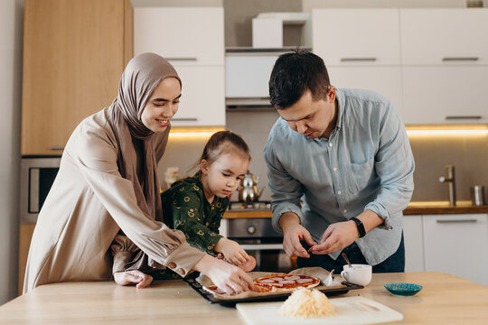 Happy Muslim family making pizza at home