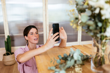 Young woman taking photo of bouquet