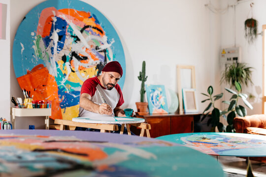 Artist painting large-format round works in his studio