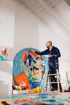 Artist painting large-format round works in his studio