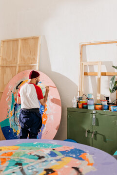 Artist painting large-format round works in his studio