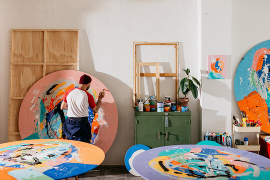 Artist painting large-format round works in his studio