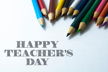 Text HAPPY TEACHER'S DAY on paper note with colorful pencils isolated on white background.