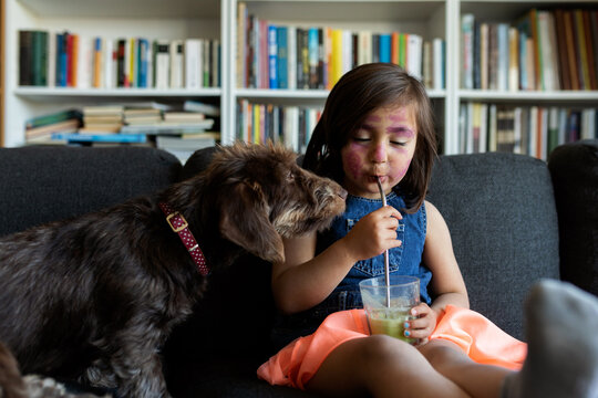 Girl drinking a juice with her dog at home