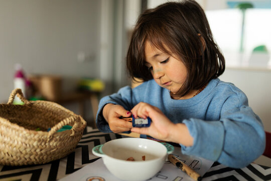 Portrait of little kid sharpening crayons in a bowl