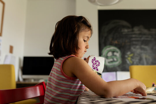 Little girl placing stickers on a picture at home