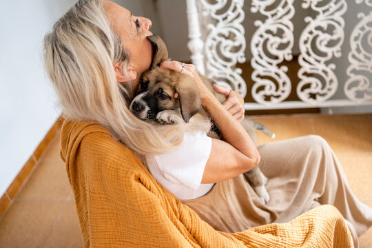 Senior woman hugging her little dog at home