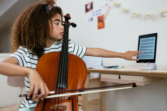 Hispanic cello student browsing notes on tablet