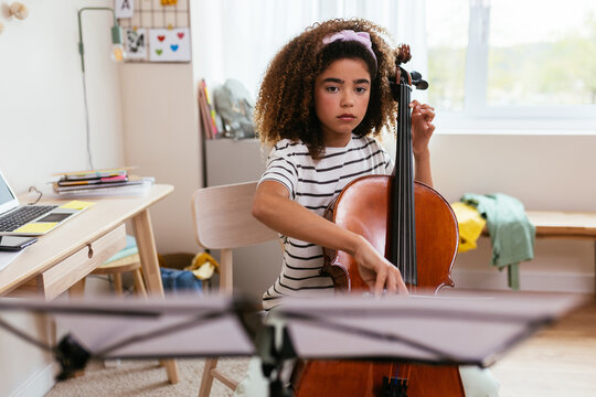 Focused Hispanic girl learning to play cello