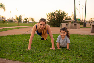 madre e hija haciendo flexiones de brazos en un parque al aire libre 
