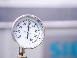 Temperature gauge for measuring instrument close up in industry zone at power plant.