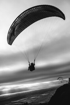 People doing parasailing over the pacific ocean at the coast of Lima, Peru (in black and white)