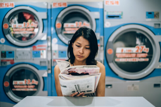 Young Asian woman waiting in a laundromat