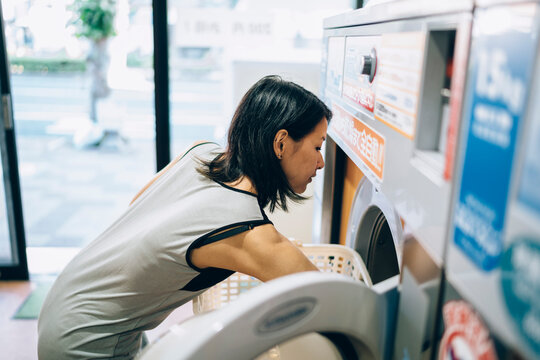 Young Asian Woman loading a washing machine in Kobe Japan